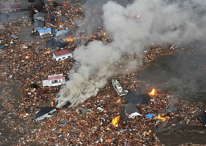Flames rise from houses and debris half submerged in tsunami in Sendai, Miyagi Prefecture (state) after Japan was struck by a strong earthquake off its northeastern coast Friday, March 11, 2011. (AP Photo/Kyodo News) JAPAN OUT, MANDATORY CREDIT, FOR COMMERCIAL USE ONLY IN NORTH AMERICA