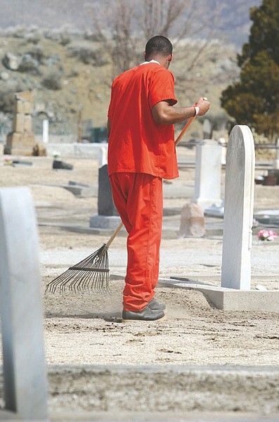 Jim Grant/Nevada AppealParticipating in a work crew, an inmate from the Carson City jail cleans up yard debris Tuesday that could foster weed growth around graves at the Lone Mountain Cemetery.