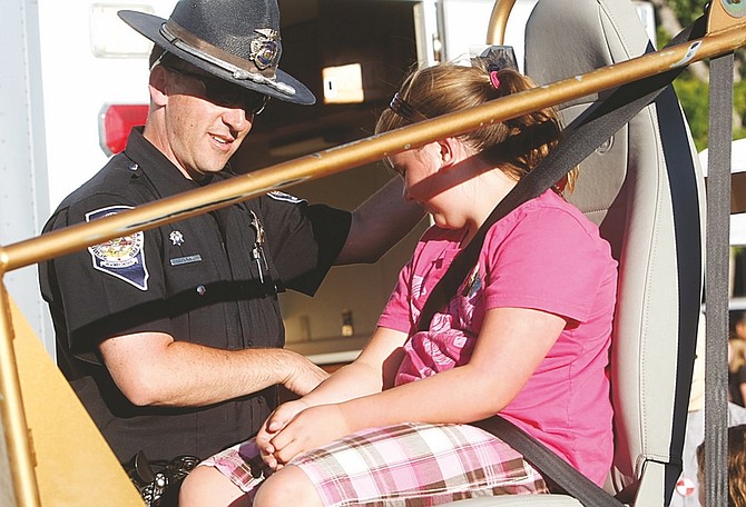 Published Caption: ABOVE: Nevada State Trooper Matthew talks to 10-year-old Cassie Franz about the convincer which illustrates how a seat belt retrains the passenger during an accident.