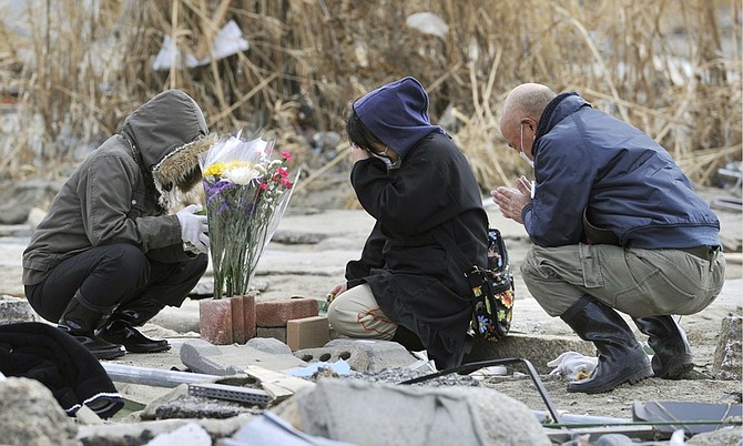 A woman, center, prays at her missing parents&#039; house devastated by a tsunami in Rikuzentakata, northern Japan Monday, April 4, 2011. (AP Photo/Kyodo News) JAPAN OUT, MANDATORY CREDIT, NO LICENSING IN CHINA, HONG KONG, JAPAN, SOUTH KOREA AND FRANCE