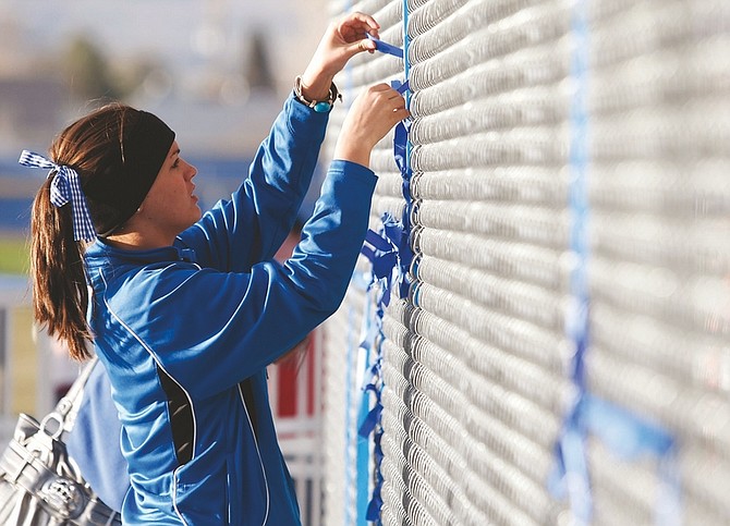 Shannon Litz/Nevada AppealCarson High junior Mary Longero ties ribbons on the fence at Carson High School in the shape of the numbers 62 and 65 at the memorial for Stephen Anderson and Keegan Aiazzi.