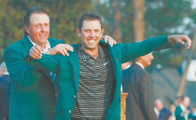 Former champion Phil Mickelson, back, helps Charl Schwartzel of South Africa with his green Masters jacket after winning the Masters golf tournament Sunday, April 10, 2011, in Augusta, Ga. (AP Photo/Matt Slocum)
