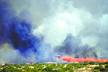 In a June 14, 2011 photo, an airplane drops retardant near a neighborhood off of Highway 92 as the Monument Fire burns in the Huachuca Mountains near Sierra Vista, Ariz. Fires have devoured hundreds of square miles in the Southwest and Texas since wildfire season began several weeks ago.  (AP Photo/Arizona Daily Star, Greg Bryan)  MANDATORY CREDIT