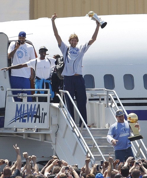 **CORRECTS BYLINE TO LM OTERO** Dallas Mavericks Dirk Nowitzki, center, of Germany raises his MVP trophy followed by teammates Jason Terry,  second from left, and Tyson Chandler, left, as they exit the charter with owner Mark Cuban carrying the NBA Championship basketball trophy after the team&#039;s arrival at Love Field in Dallas, Monday, June 13, 2011. The Mavericks beat the Heat to win the NBA championship.  (AP Photo/LM Otero)