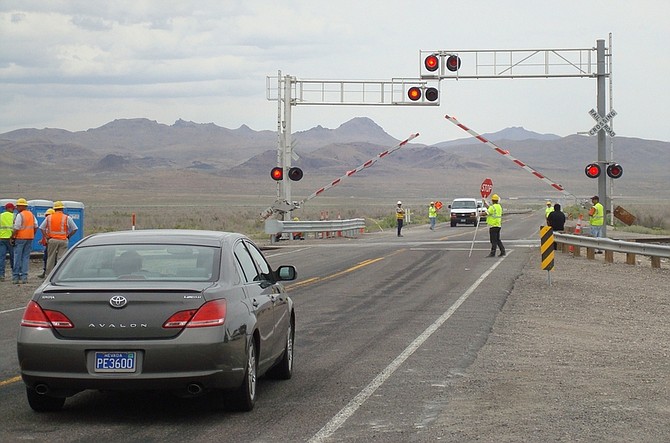 In this photo taken  June 28, 2011, Nevada state transportation officials join investigators for the National Transportation Safety Board near Fallon, Nev., to conduct tests and examine new crossing guard equipment where a truck slammed into an Amtrak train on June 24. The crash killed the truck driver, a conductor and four others on the train. Investigators closed the highway in 30-minute intervals most of the day to check the equipment and measure distances for the safety investigation at the crossing. (AP Photo/Scott Sonner)