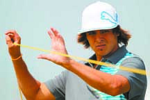 Rickie Fowler of the US lifts up the course ropes during a practice round ahead of the British Open Golf Championship at Royal St George&#039;s golf course in Sandwich, England, Monday, July 11, 2011. (AP Photo/Tim Hales)