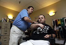 In this photo taken Dec. 13, 2010, quadriplegic Adam Martin, right, works with physical therapist Wes Bower at the Sarasota Health and Rehabilitation Center, the nursing home where he lives. It&#039;s no longer unusual to find a nursing home resident who is decades younger than his neighbor: About one in seven people now living in such facilities in the U.S. is under 65. (AP Photo/Chris O&#039;Meara)