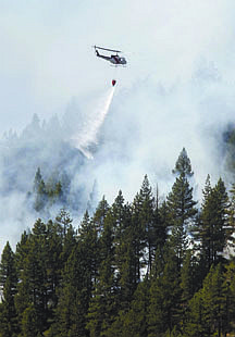 Shannon Litz/Nevada AppealA helicopter drops water on a fire on Spooner on Thursday.