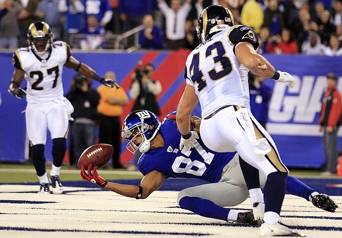 New York Giants wide receiver Domenik Hixon (87) catches a pass for a touchdown during the second quarter of an NFL football game against the St. Louis Rams on Monday, Sept. 19, 2011, in East Rutherford, N.J. Defending are Rams&#039; Craig Dahl, right, and Quintin Mikell. (AP Photo/Julio Cortez)