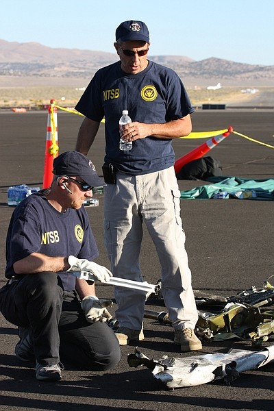 In this handout photo from the National Traffic Safety Board taken Sunday, Sept. 18, 2011 at an airfield in Reno, Nev., shows two NTSB officials looking at wreckage from Jimmy Leeward&#039;s plane that crash on Friday. Officials say nine people died.  (AP Photo/National Traffic Safety Board, HO)