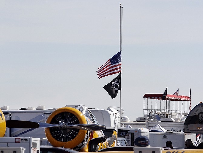 American flag and the POW flag fly at half-staff as a grandstand is shown in background and a plane rests in the foreground at the Reno Air Races in Reno, Nev., Saturday, Sept. 17, 2011. The Reno Air Races were canceled after a fatal plane crash on Friday. (AP Photo/Paul Sakuma)