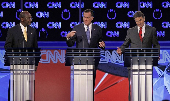 Republican presidential candidates businessman Herman Cain, left, watches as former Massachusetts Gov. Mitt Romney, center, and Texas Gov. Rick Perry speak during a Republican presidential debate Tuesday, Oct. 18, 2011, in Las Vegas.  (AP Photo/Chris Carlson)