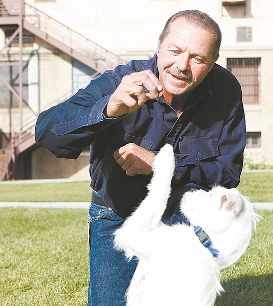 Shannon Litz/Nevada Appeal Fred Stites works on teaching Banjo a trick on Friday at the Nevada State Prison. Both are part of the Puppies Up for Parole program to help shelter dogs become more adoptable.