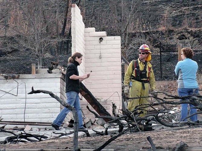 Austin Hardage, 23, left, returns, Saturday, Nov. 19, 2011 to the charred rubble that used to be the home where he and his wife, Sarah Hardage, 22, lived in an upscale community in the Sierra foothills in southwest Reno, Nev. before a wildfire destroyed that home and 31 others early Friday.(AP Photo/Scott Sonner)