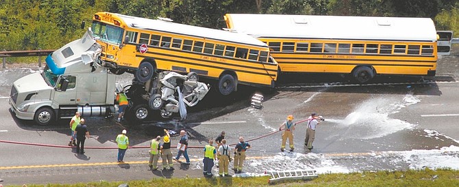 In this Aug. 5, 2010 photo, a crumpled pickup truck is seen between two St. James School District buses and a tractor-trailer on Interstate 44 near Gray Summit, Mo. Citing the wreck, in which investigators say the 19-year-old pickup driver was texting, federal transportation leaders this week pressed states to ban cell phone use by drivers. Despite the dangers, states appear unlikely to oblige. (AP Photo/St. Louis Post-Dispatch, Robert Cohen)  EDWARDSVILLE INTELLIGENCER OUT; THE ALTON TELEGRAPH OUT