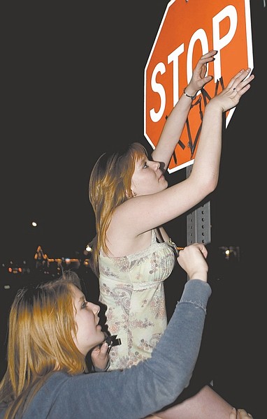 Shannon Litz/Nevada AppealMiranda Callahan hands Candace Whitmire tape  to spell out &quot;Kony&quot; on a stop sign in Carson City on Friday night as part of Cover the Night.