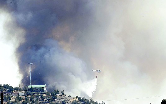 Shannon LitzA helicopter dumps water on the fire south of Ray May Way on Friday afternoon.