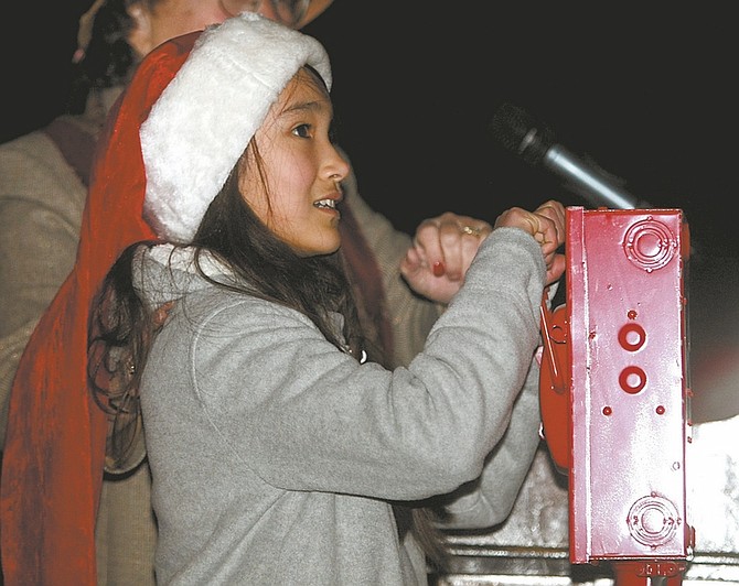 Shannon Litz / Nevada AppealMark Twain Elementary School fifth-grader Josephine Payan, 11, flips the switch to turn on the Christmas lights at the Capitol on Friday evening during the annual Silver and Snowflakes Festival of Lights.