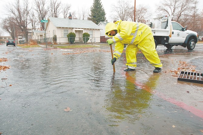 Eric Engles, with Carson City Public Works, clears a storm drain in Carson City, Nev, as a heavy, wet storm hits the Northern Nevada region on Sunday, Dec. 2, 2012. (AP Photo/Cathleen Allison)