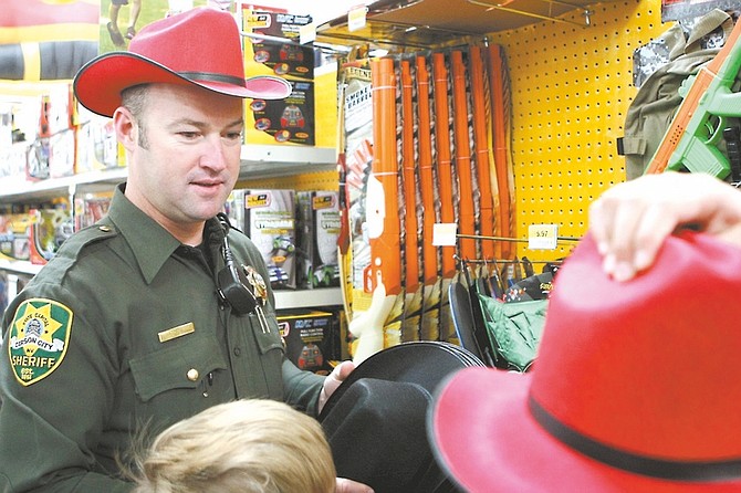 Shannon Litz / Nevada AppealCarson City Sheriff&#038;#8217;s Deputy Craig Erven, who shopped with Cesar and Weston at Walmart on Thursday morning, found cowboy hats to wear during the event.