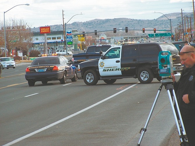 Trooper Kris Satterwhite mapping the crash scene with Sokkia equipment while parked emergency vehicles surround and protect the victim from being seen until the coroner completes his portion of the on-scene investigation.