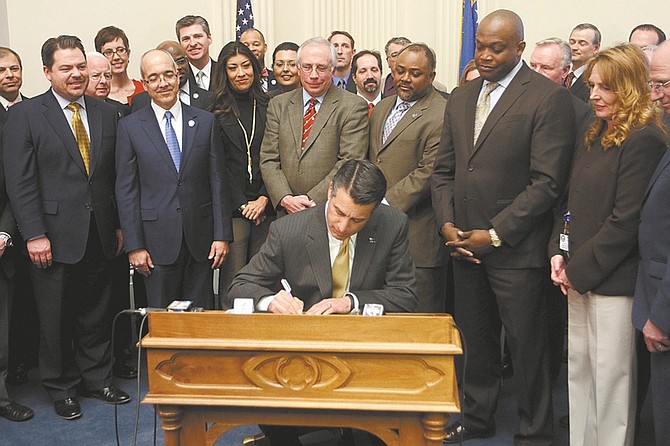 Shannon Litz / Nevada AppealGov. Brian Sandoval signs the online gaming bill on Thursday afternoon in the old Assembly chambers of the Capitol while members of the Nevada Senate and Assembly look on.