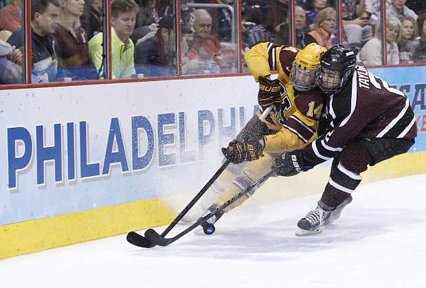 Minnesota&#039;s Tom Serratore, left, and Union&#039;s Jeff Taylor, right, battle for the puck along the boards during the second period of an NCAA men&#039;s college hockey Frozen Four tournament game on Saturday, April 12, 2014, in Philadelphia. (AP Photo/Chris Szagola)