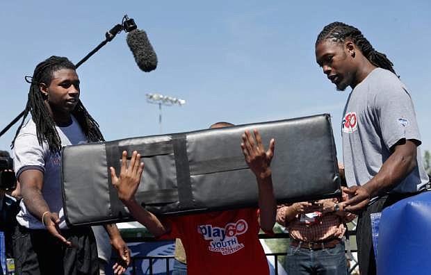 South Carolina&#039;s Jadeveon Clowney, right, and Clemson&#039;s Sammy Watkins teach tackling technique during an NFL football event in New York, Wednesday, May 7, 2014. The event was to promote Play 60, an NFL program which encourages kids to be active for a healthy life. (AP Photo/Seth Wenig)