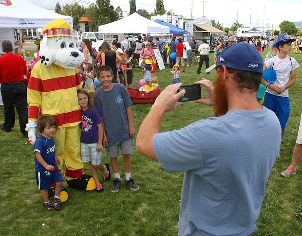 Trevor Rotoli snaps a picture of his children, Levino, 3, Sophia, 6, and Seth, 11, with Sparky at the National Night Out event on Tuesday.