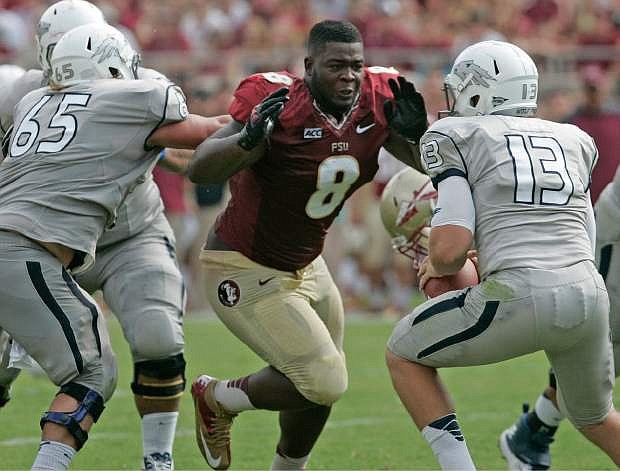 Florida State&#039;s Timmy Jernigan (8) loses his helmet as he rushes Nevada&#039;s quarterback Devin Combs (13) in the second quarter of an NCAA college football game on Saturday, Sept. 14, 2013, in Tallahassee, Fla. (AP Photo/Steve Cannon)