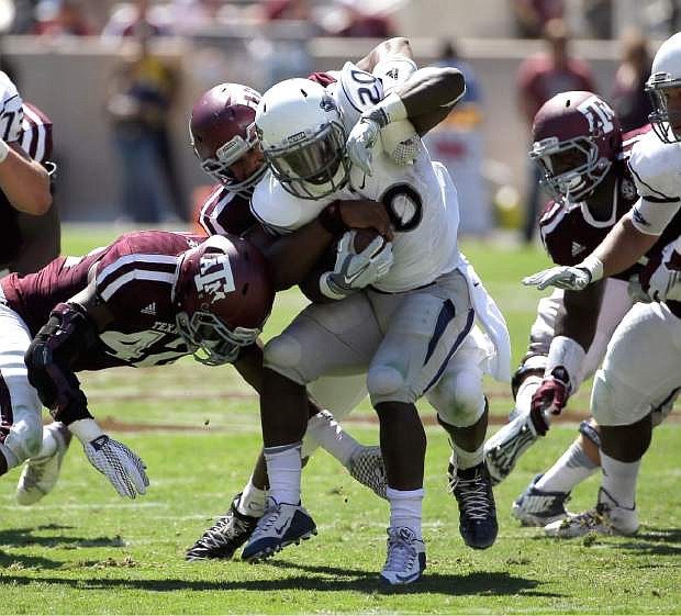 Nevada running back James Butler (20) is wrapped up by Texas A&amp;M defensive lineman Myles Garrett, rear, and linebacker Otaro Alaka (42) during the first half of an NCAA college football game, Saturday, Sept. 19, 2015, in College Station, Texas. (AP Photo/David J. Phillip)