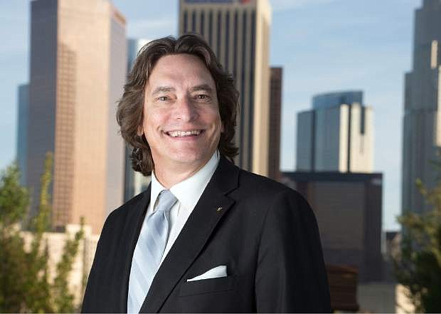 In this April 8, 2014 photo provided by the Los Angeles Register, editor Ron Sylvester poses for a photo with the Los Angeles skyline in the background. Former greeting card executive Aaron Kushner is trying to turn the Orange County Register into a media giant in southern California, largely driven by paper and ink. The unconventional effort gets a jolt Wednesday, April 16, 2014, when Freedom Communications Inc., the company Kushner bought with other investors two years ago, launches the Los Angeles Register. (AP Photo/Los Angeles Register, Leonard Ortiz)