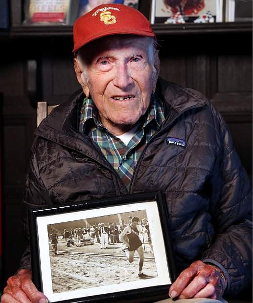 This Jan. 21, 2014 photo provided by USC Dornsife College of Letters, Arts and Sciences, Louis Zamperini displays one of his photographs as a student and sprinter, at his Los Angeles home. Zamperini, a U.S. Olympic distance runner and World War II veteran who survived 47 days on a raft in the Pacific after his bomber crashed, then endured two years in Japanese prison camps, died Wednesday, July 2, 2014, according to Universal Pictures studio spokesman Michael Moses. He was 97.  (AP Photo/Matt Meindl/USC Dornsife College of Letters, Arts and Sciences)