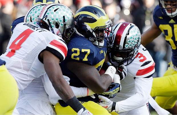 Michigan running back Derrick Green (27) is stopped by Ohio State safety C.J. Barnett (4) and defensive back Corey Brown (3) during the first quarter of an NCAA college football game in Ann Arbor, Mich., Saturday, Nov. 30, 2013. (AP Photo/Carlos Osorio)