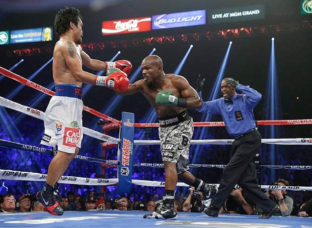 Manny Pacquiao, left, of the Philippines, evades a punch from Timothy Bradley in their WBO welterweight title boxing fight Saturday, April 12, 2014, in Las Vegas. At right is referee Kenny Bayless. (AP Photo/Isaac Brekken)