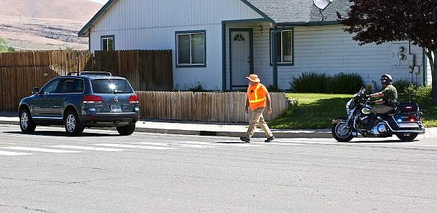 Civilian employee for the CCSO, Don Quilici, walks across a crosswalk on Fairview Drive near as motor officer Deputy Joey Trotter pursues a vehicle that failed to stop for him Thursday morning.