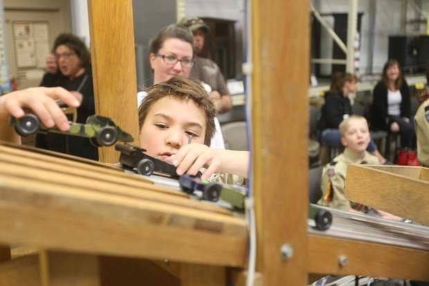 Nine-year-old Ben Kahue places pinewood derby cars on the track at The Home Depot on Saturday afternoon during the annual Cub Scouts Pack 341 event.