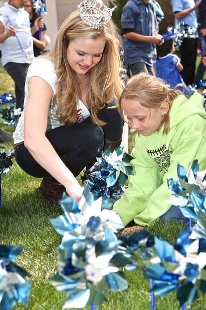 Miss Carson City Briana Neben and Gracie Fields, 8, put a pinwheel in the ground in observation of Pinwheels For Prevention as April begins National Child Abuse Prevention month.