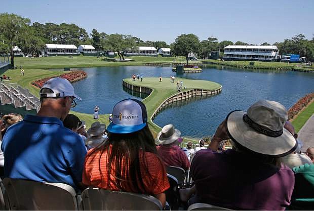 Spectators watch golfers on the 17th green during a practice round for The Players championship golf tournament at TPC Sawgrass in Ponte Vedra Beach, Fla., Tuesday, May 6, 2014. (AP Photo/John Raoux)