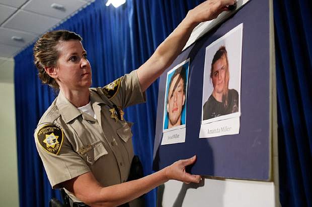 Las Vegas Metropolitan Police Department Officer Laura Meltzer hangs up pictures of suspects Jerad Miller and Amanda Miller before a news conference Monday, June 9, 2014 in Las Vegas. Two police officers were having lunch at a strip mall pizza buffet when the Millers fatally shot them in a point-blank ambush, then fled to a nearby Wal-Mart where they killed a third person and then themselves in an apparent suicide pact, authorities said. (AP Photo/John Locher)
