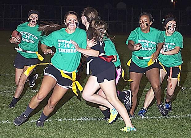 Junior running back Kyla Kincaid, left, follows the blocks of Miranda Ford, second from left, Courtney Cross and Nichole Mariezcurrena as senior Maddie Dirickson goes in for the tackle during the junior&#039;s 21-0 in the annual Powder Puff game on Monday.