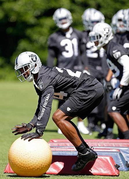 Oakland Raiders defensive back Charles Woodson makes his way through an obstacle course during their NFL football training camp on Saturday, July 27, 2013, in Napa, Calif. Defensive back Coye Francies (31) looks on. (AP Photo/Eric Risberg)