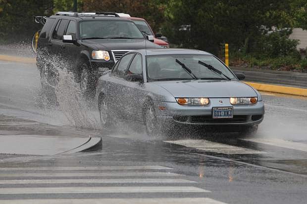 Motorists splash through a puddle at the intersection of Fairview Drive and Roop Street on Monday. More rain is in the forecast for today.