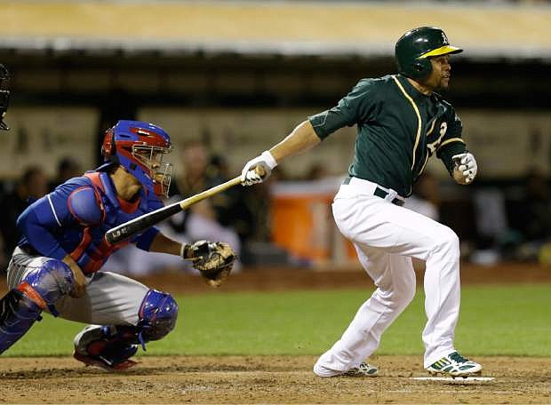 Oakland Athletics&#039; Coco Crisp swings for an RBI double off Texas Rangers&#039; Nick Martinez in the fourth inning of a baseball game Tuesday, April 22, 2014, in Oakland, Calif. At left is Rangers catcher Robinson Chirinos. (AP Photo/Ben Margot)