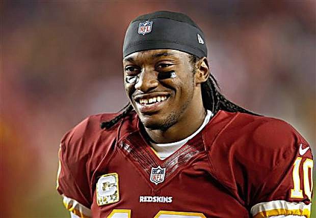 FILE - In this Nov. 25, 2013 file photo, Washington Redskins quarterback Robert Griffin III smiles as he walks along the sidelines before an NFL football game against the San Francisco 49ers in Landover, Md. Griffin III will drive the pace car before Saturday night&#039;s, April 26, 2014 NASCAR race at Richmond. Richmond International Raceway made the announcement Wednesday, April 23, 2014. (AP Photo/Evan Vucci, File)