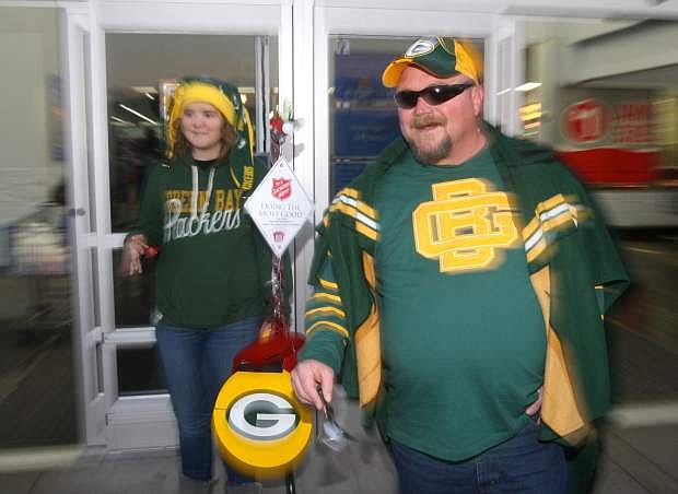 Green Bay Packer fans Chris Ostrander and Rebecca Ostrander ring bells for the Salvation Army Red Kettle program in front of the Topsy Lane Walmart on Monday.