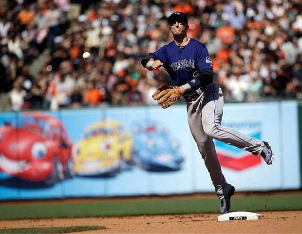 Colorado Rockies shortstop Troy Tulowitzki makes an off-balance throw to put out San Francisco Giants&#039; Buster Posey at first base during the seventh inning of a baseball game on Saturday, April 12, 2014, in San Francisco. (AP Photo/Marcio Jose Sanchez)