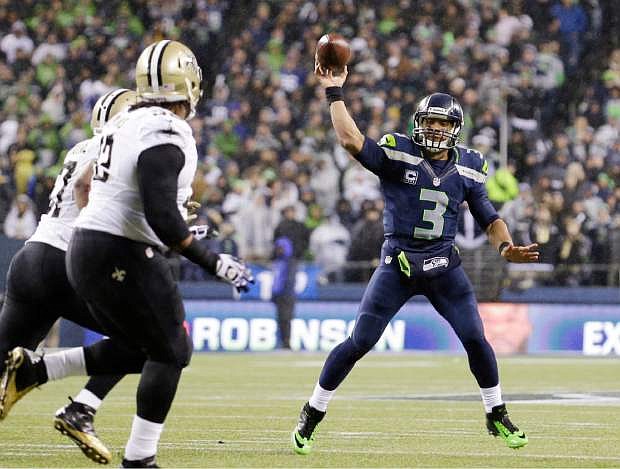 Seattle Seahawks quarterback Russell Wilson (3) throws against the New Orleans Saints in the first half of an NFL football game, Monday, Dec. 2, 2013, in Seattle. (AP Photo/Elaine Thompson)
