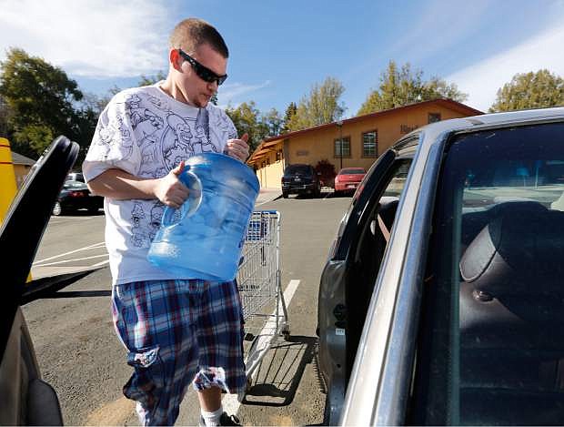 FILE - In this Feb. 4, 2014 file photo, Forrest Clark loads five-gallon bottles of water purchased at a local store into his car in Willits, Calif. State public health officials have reduced the number of communities at risk of losing their drinking water due to California&#039;s drought from 17 to three. In the Mendocino County town of Willits, which was two months from losing its drinking water, well drilling efforts and rain have helped officials ease restrictions. (AP Photo/Rich Pedroncelli, file)