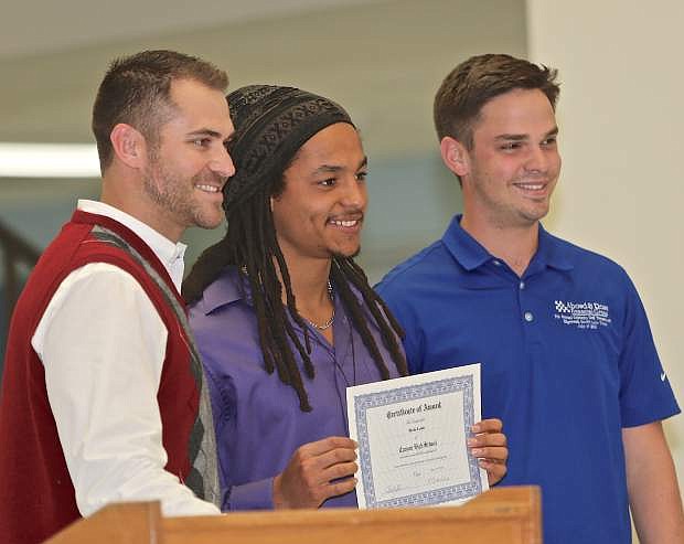 Ikela Lewis, center, receives a leadership scholarship from Eric Abowd and Steve Rose of the Awbowd &amp; Rose Financial Group on May 19 at Carson High School.